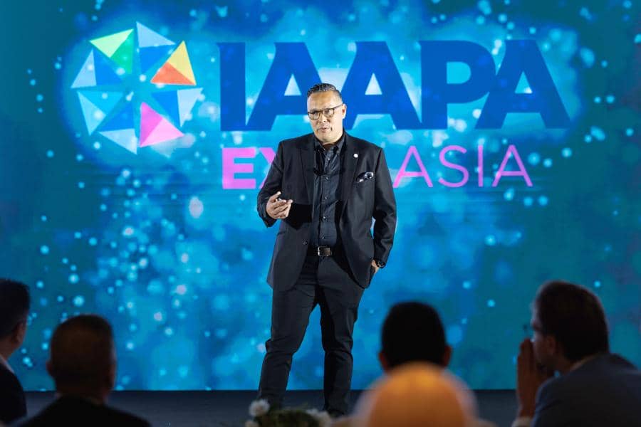 Greg Yong standing on stage in Bangkok addressing crowd